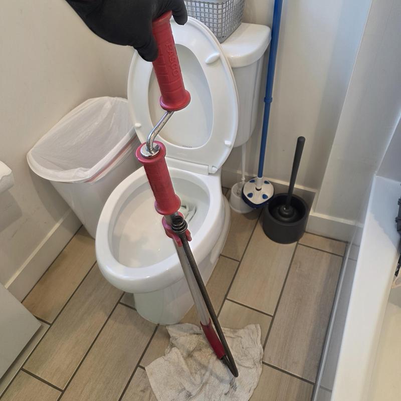 Toilet drain snake clearing blockage in bathroom restroom