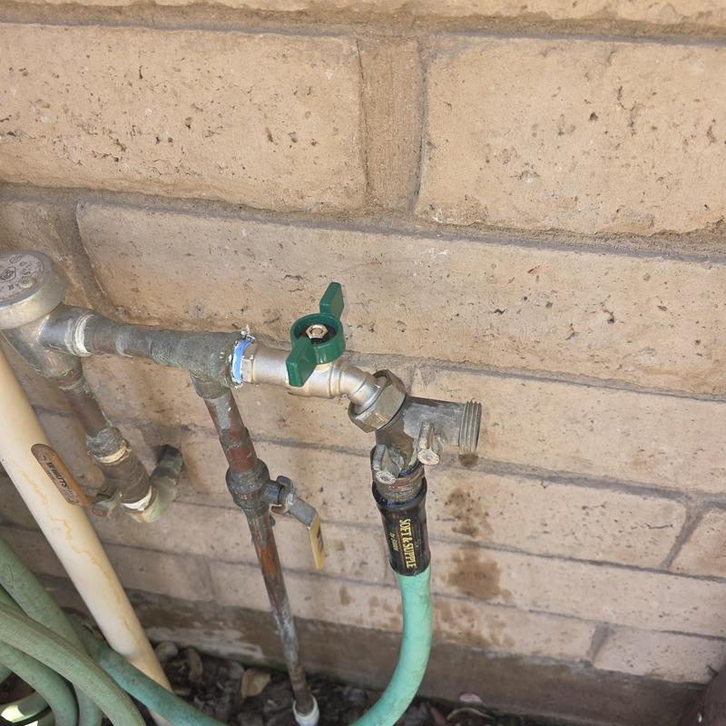 Hose bib with green handle and attached garden hose