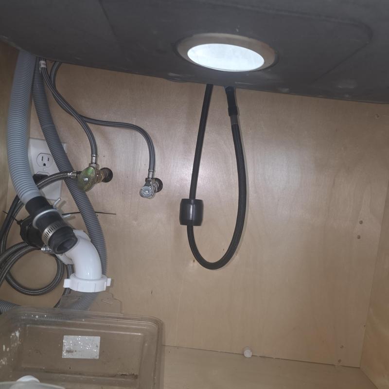 Garbage disposal plumbing and dishwasher drain hoses under sink