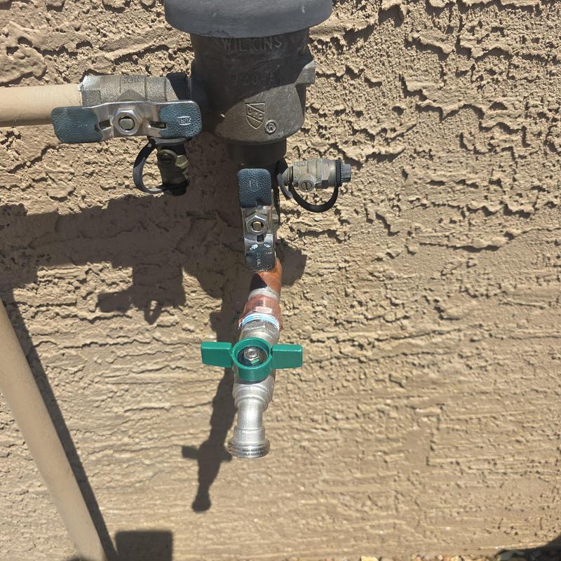 Hose bib replacement with green handle on stucco wall